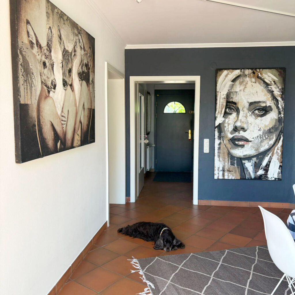 Surreales Kunstwerk mit Rehen und Frauenporträt an dunkler Wand im Flur