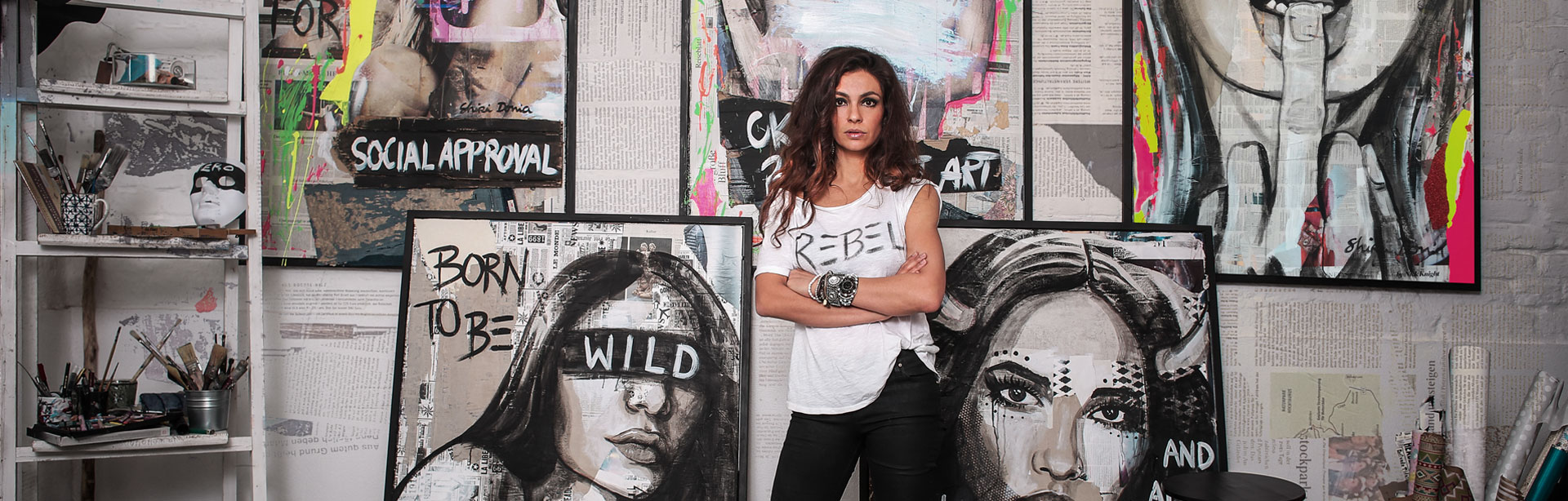Shirin Donia vor Porträtgemälden der Serie Rebel