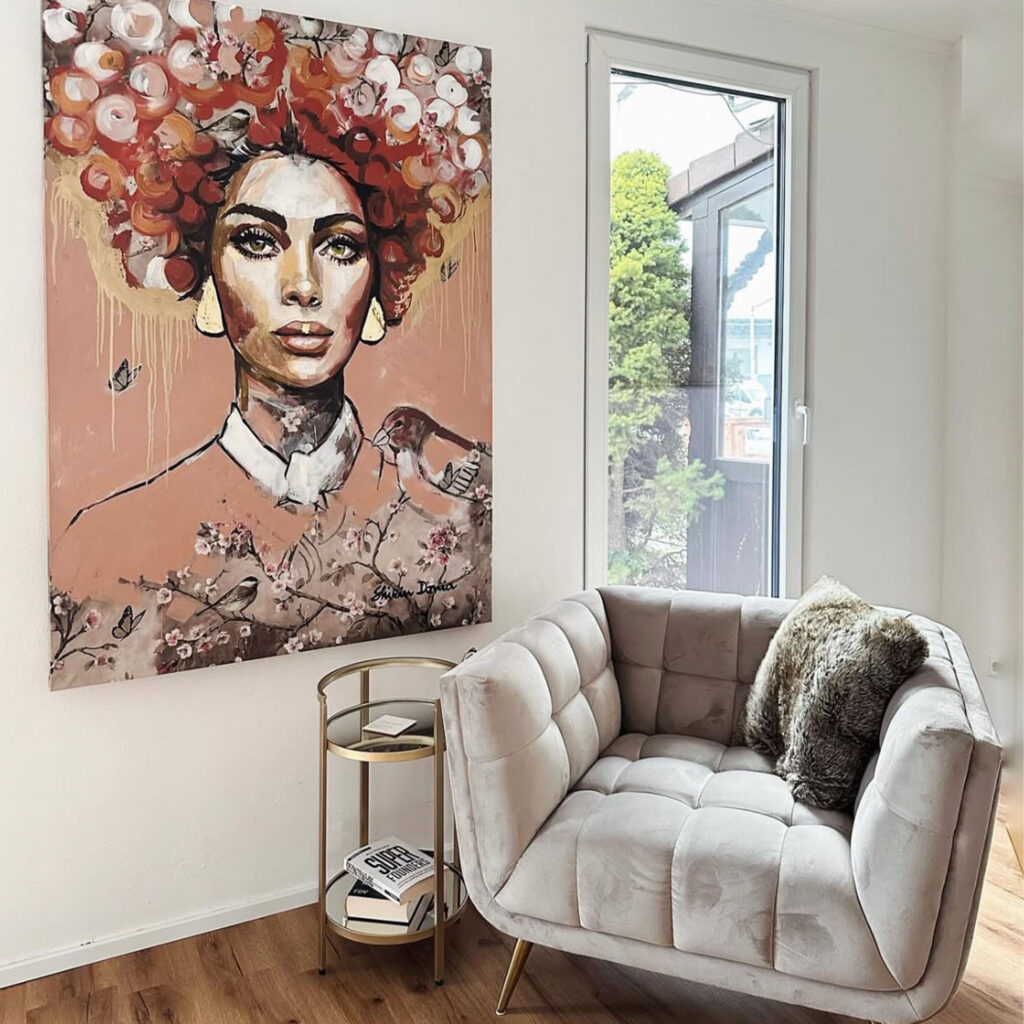 Kunstwerk mit blumengeschmückter Frau und Vögeln neben Samtsessel